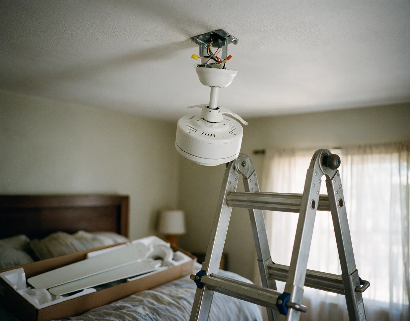 A new ceiling fan motor mounted on a bedroom ceiling